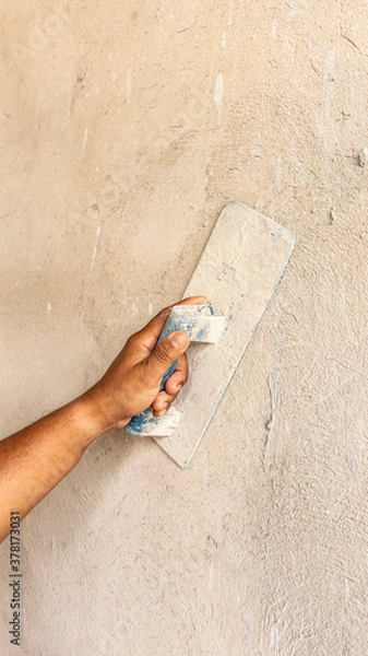 Fototapeta Tiler's hand.bricklayer plaster a wall inside a building