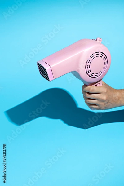 Obraz Layout made with pink hairdryer on blue background. Retro vintage 60's and 70's aesthetic with summer shadows. Minimal hairdressing concept. Flat lay.