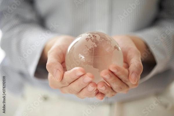 Fototapeta 透明の地球儀を持つ女性の手元