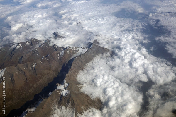 Fototapeta Top view of the mountain peaks of the Alps, covered by clouds or snow