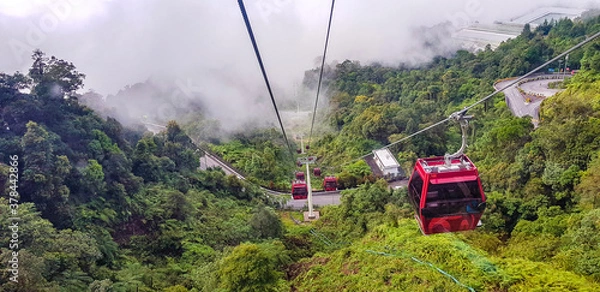 Obraz cable car at genting highlands, malaysia in a foggy weather with green grass visible from inside cable car