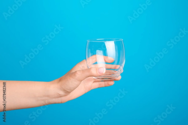 Fototapeta Hand with empty glass on color background