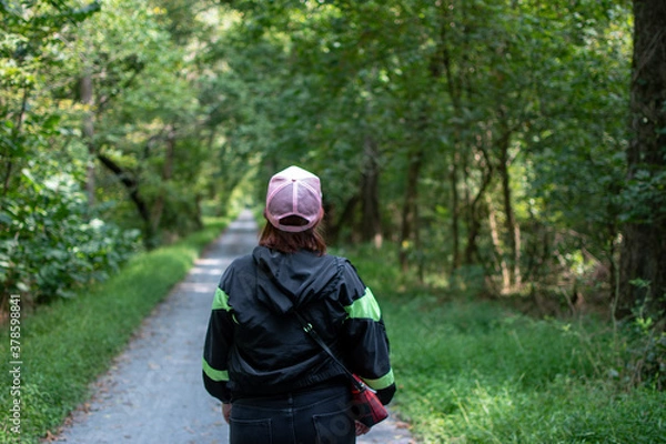 Fototapeta person walking in the woods along a path