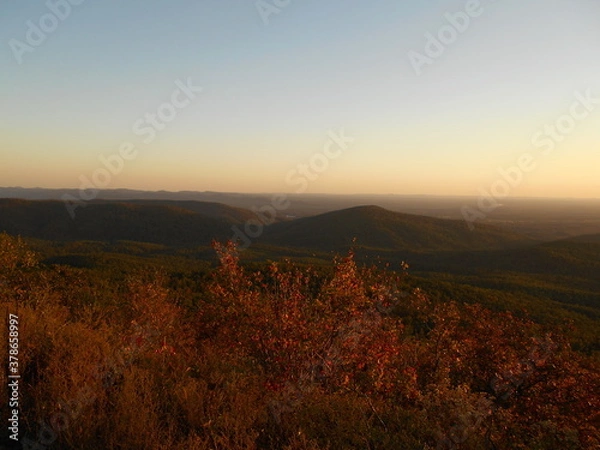 Fototapeta Looking across a colorful mountain valley in the evening one late autumn	