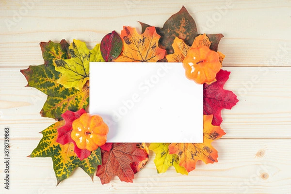 Fototapeta Orange pumpkins, maple leaf, berries and mock up paper blank on wooden background. Hello Fall greeting card, autumn time concept. Flat lay. Copy space
