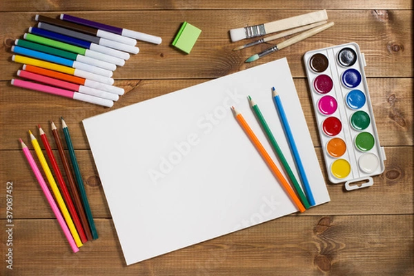 Fototapeta Assortment of stationery for drawing on wood background. Colored pencils, paints, felt tips, brushes for children's creativity. Copy space. Top view. Flat lay