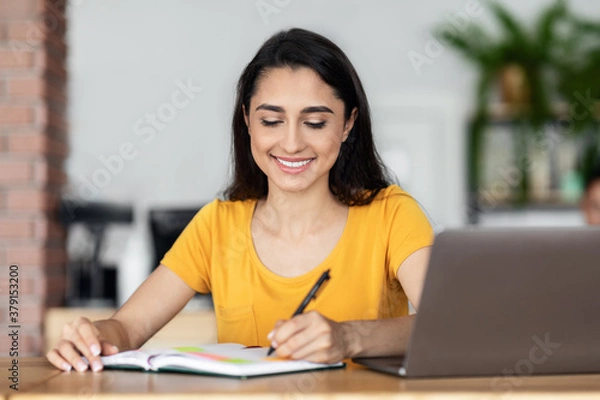 Obraz Smiling arab lady working online at cafe