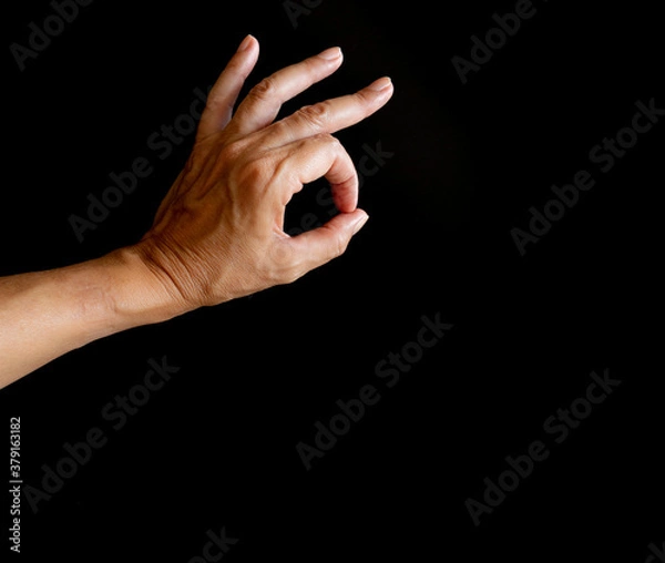 Obraz Mano con tres dedos levantados y dos haciendo un círculo de ok, sobre fondo negro.