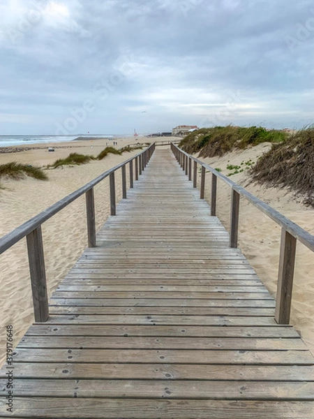 Fototapeta Boardwalk crossing the sand dunes in Costa Nova, Portugal with the ocean on the background