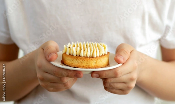 Fototapeta Selective focus to a child holding in hands a plate with vanilla cake.