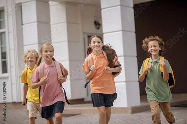 Fototapeta Schoolchildren with backpacks running home after lessons