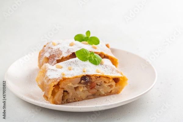 Fototapeta Apple strudel with raisins,  peanuts and cinnamon. South Tyrol recipe. Light background. Copy space. Minimalistic.