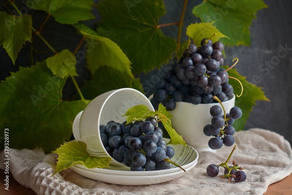 Fototapeta Grapes on a white saucer and a dark background.