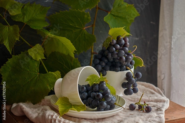 Fototapeta Grapes on a white saucer and a dark background.