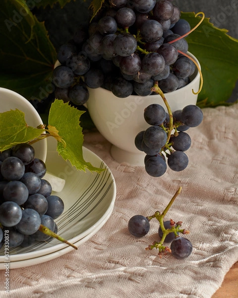 Fototapeta Grapes on a white saucer and a dark background.