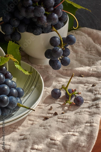 Fototapeta Grapes on a white saucer and a dark background.