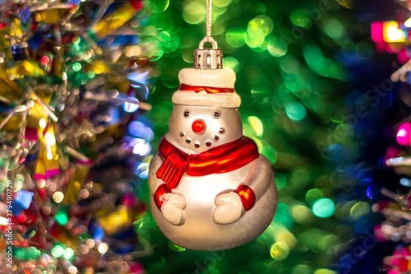 Fototapeta Vintage old Soviet Christmas tree toy (snowman) on the background of a Christmas tree and New Year's multi-colored tinsel.
