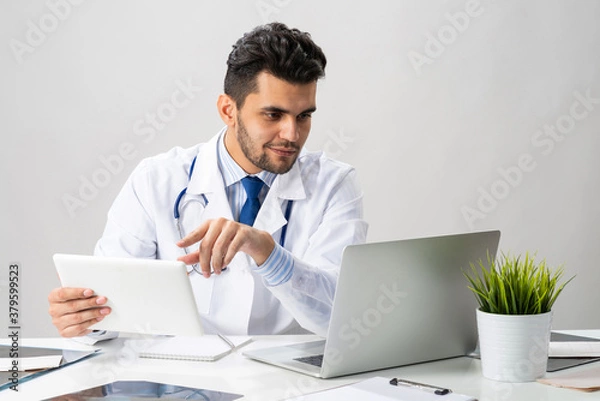 Obraz Young arab internist working with tablet computer
