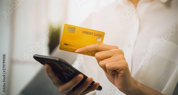 Fototapeta Hand holding smartphone and using application shopping online with payment by credit card online.