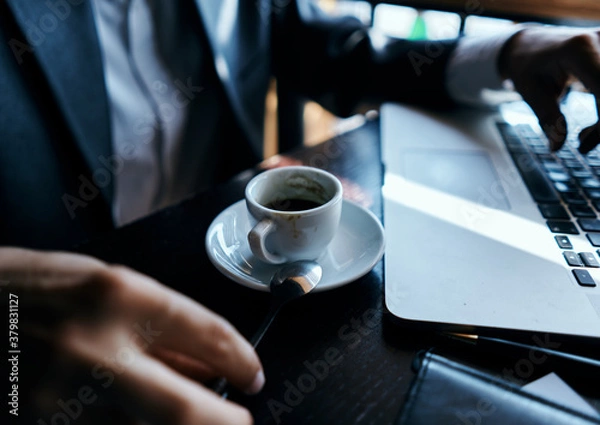 Fototapeta business man in a cafe at the table in front of a laptop work a cup of coffee at the table communication technology