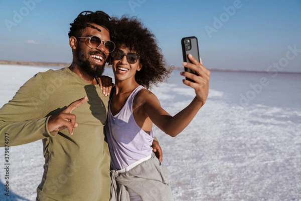Fototapeta Image of happy african american couple taking selfie on mobile phone
