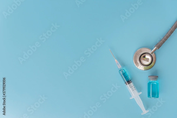 Fototapeta A concept of  against virus covid-19 corona virus,  a syringe with liquid vaccines and stethoscope with blue background.