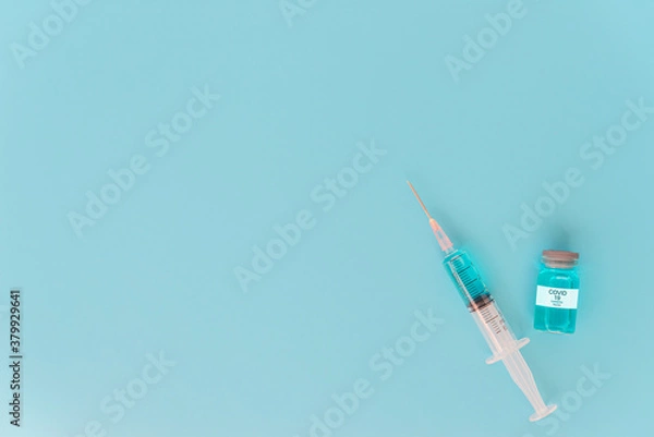 Fototapeta A concept of  against virus covid-19 corona virus,  a syringe with liquid vaccines and with blue background. Top view.