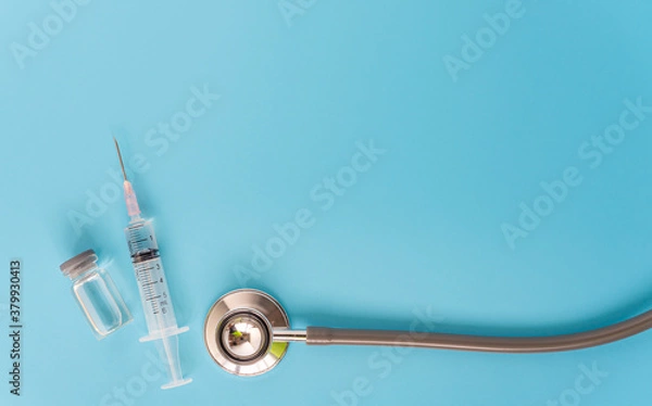 Fototapeta A concept of  against virus covid-19 corona virus,  a syringe with liquid vaccines and stethoscope with blue background,top view.