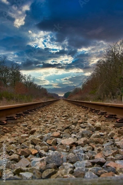 Fototapeta Straight railroad under a dramatic sky