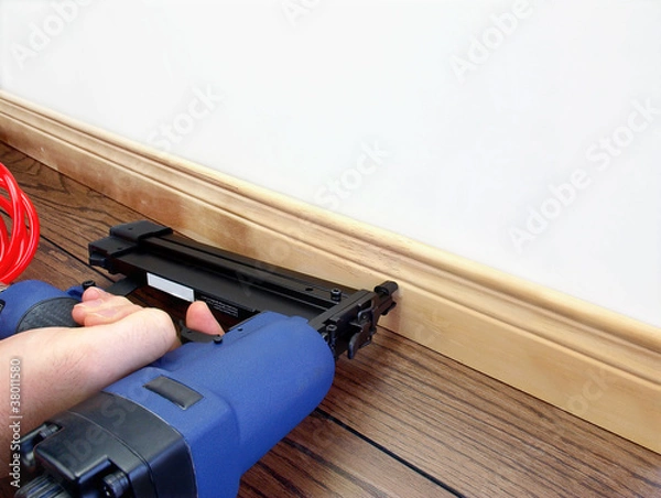 Obraz Male hand with carpenter tool installing baseboard