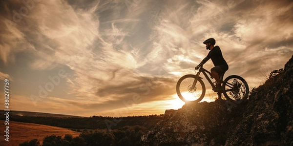 Fototapeta Man on mountain bike against sundown sky