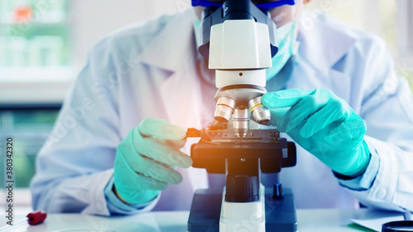 Fototapeta Scientist or doctor use microscope to test for the coronavirus (COVID 19). Or a new flu virus to save people life In the lab Or hospital. Success in research the treatment of patient
