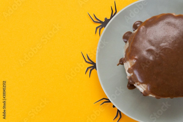 Obraz Halloween concept, trick or treat. Spiders from paper crawl out from under a plate. Chocolate cake lies on the right. Orange background, homemade confectionery. Copy space, flat lay. Selective focus.