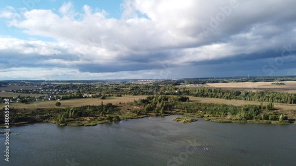 Fototapeta A view from a height of a beautiful calm shore of a forest lake