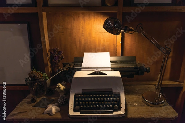 Obraz The old typewriter on the wooden desk under the light of the lamp background.