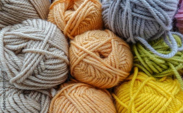Obraz Colorful woolen balls of yarn. Background of colored yarn balls. Needlework. Knitting. Hobby and leisure. Balls of yarn in neutral, light orange, grey, light green, yellow colors.