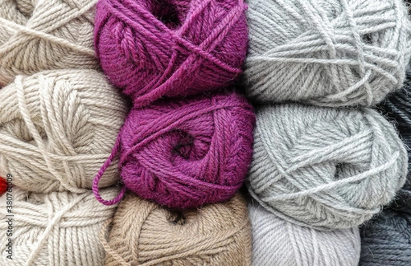 Obraz Colorful woolen balls of yarn. Background of colored yarn balls. Needlework. Knitting. Hobbies and leisure. Balls of yarn in shades of neutral, lilac, grey, khaki colors.