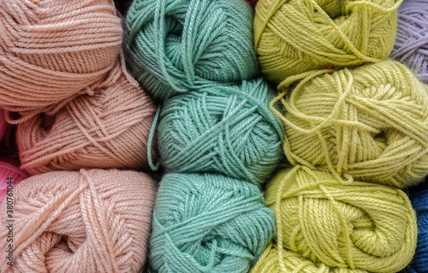 Obraz Colorful woolen balls of yarn. Background of colored yarn balls. Needlework. Knitting. Hobbies and leisure. Balls of yarn in light pink, light grey, light green colors.