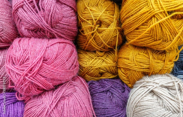 Obraz Colorful woolen balls of yarn. Background of colored yarn balls. Needlework. Knitting. Hobby and leisure. Balls of yarn in gold, white, pink colors.