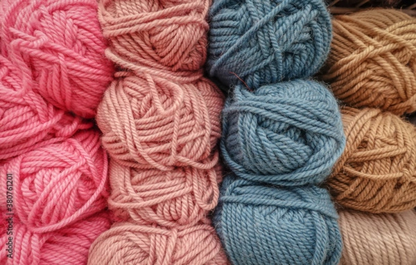 Obraz Colorful woolen balls of yarn. Background of colored yarn balls. Needlework. Knitting. Hobbies and leisure. Balls of yarn in pink, blue-grey, salmon and tan colors.