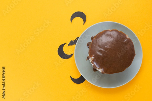 Obraz Bat and moon under a plate. Chocolate cake on orange background. Halloween concept, trick or treat. Handmade cooking. Copy space, flat lay. Selective focus, blur.