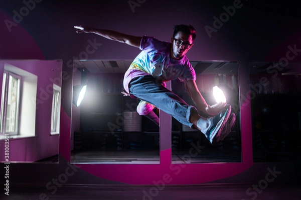 Fototapeta Professional break dancer in motion, practicing modern hip-hop dance in pink neon light