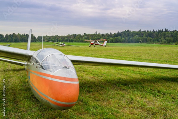 Obraz a glider is landed on a green grass of  an airdrome field in russian countryside