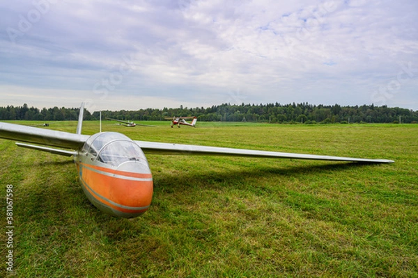 Obraz a glider is landed on a green grass of  an airdrome field in russian countryside