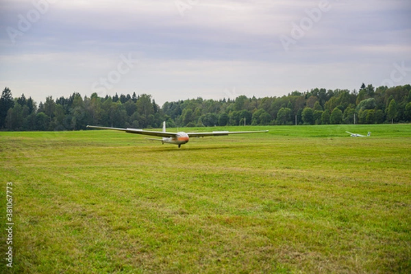 Obraz a glider is landed on a green grass of  an airdrome field in russian countryside