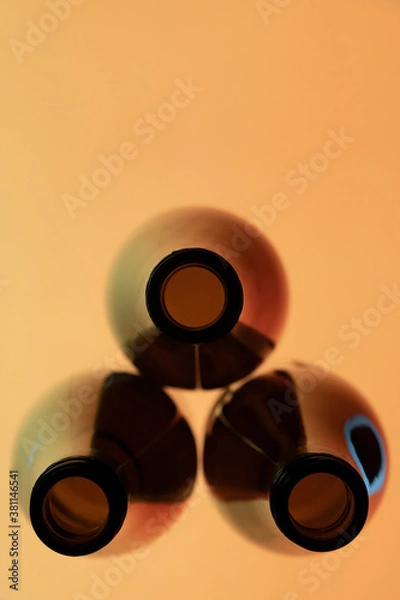 Obraz Three wine bottles viewed from top in a triangle  with a brown background