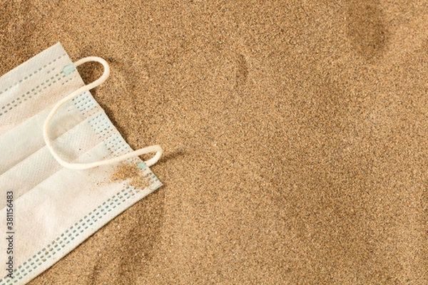 Fototapeta Waste during COVID-19. Scrapped to ocean coronavirus single-use face masks. Environmental and coastal plastic pollution. Trash on the beach that threatens the health of the oceans.