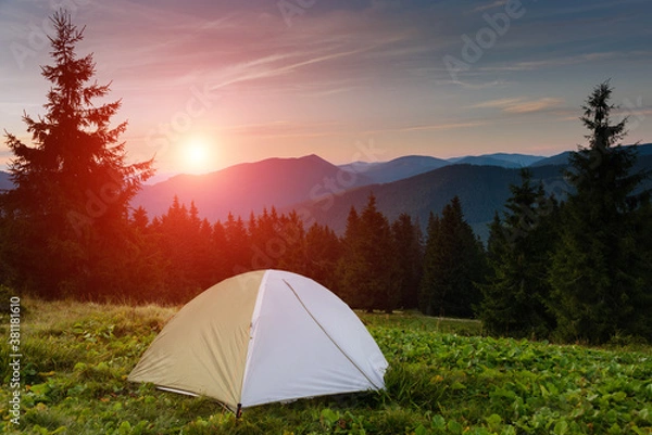 Fototapeta Summer landscape. Tourist tent in camp among meadow in the mountains at sunset. View of the dramatic evening sky. Red sunset and mountains in the background.