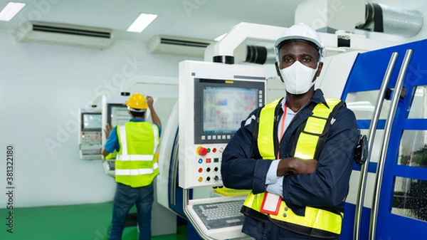 Fototapeta Portrait of African American engineer worker wearing surgical mask and arms crossed in factory. Technician standing in front of CNC Milling, Lathe Machine. Concept of business Industrial manufacturing