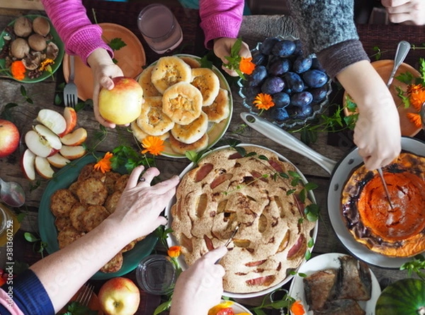 Fototapeta Thanksgiving Day. Festive served table, dishes with fried pumpkin, pies, fruits, berries and vegetables on a wooden background. Hands of guests over the table. Rustic style.